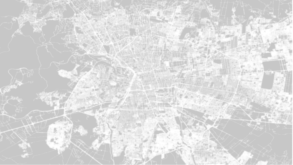 A blurred map of an urban area, displaying various streets and blocks with a grayscale color scheme.